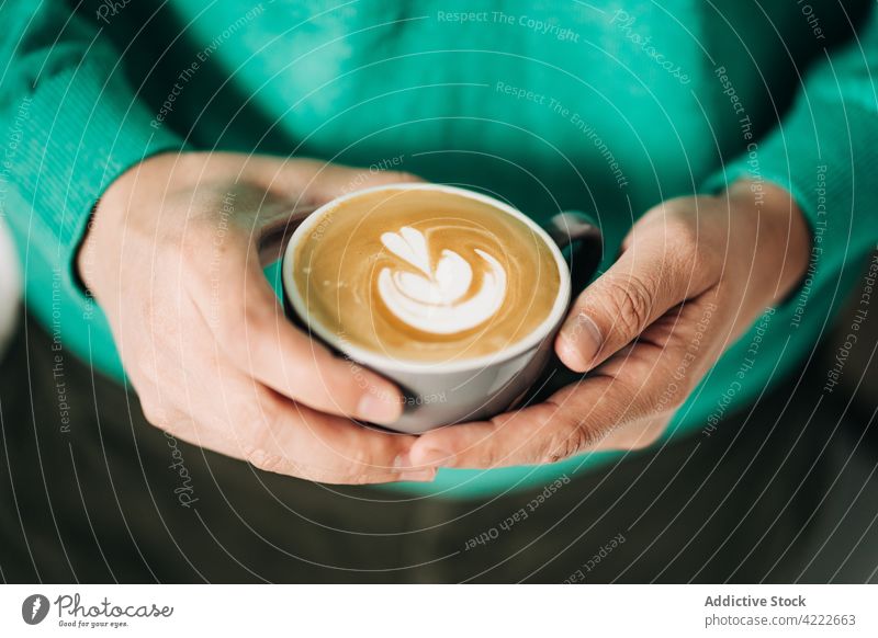 Crop person with cup of delicious latte coffee latte art hot drink beverage milk aroma natural fresh ceramic material froth dairy product scent tasty fragrant