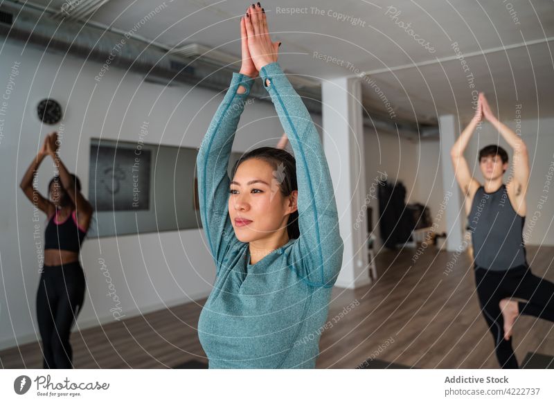Woman practicing yoga during group lesson in studio class woman practice people together mountain pose wellness asana calm zen outstretch arms energy sportswear