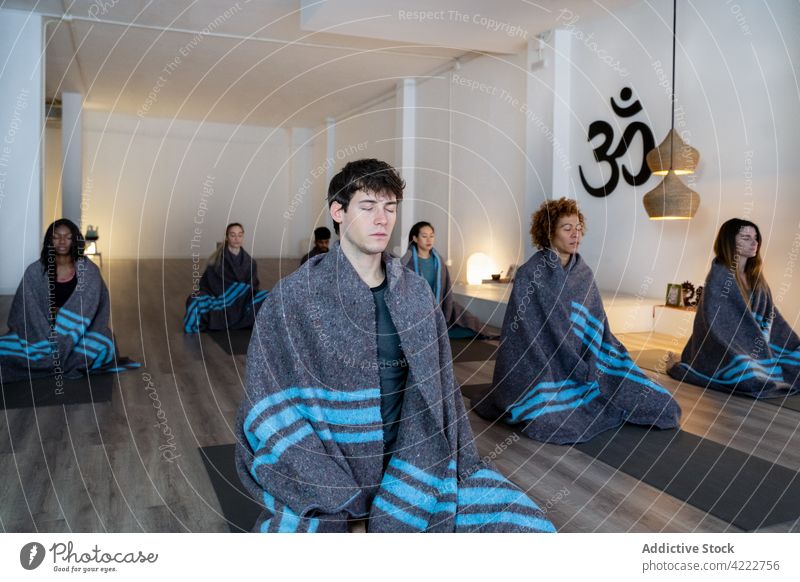 Group of people meditating in yoga studio meditate class together tranquil zen plaid blanket harmony multiracial multiethnic diverse black african american