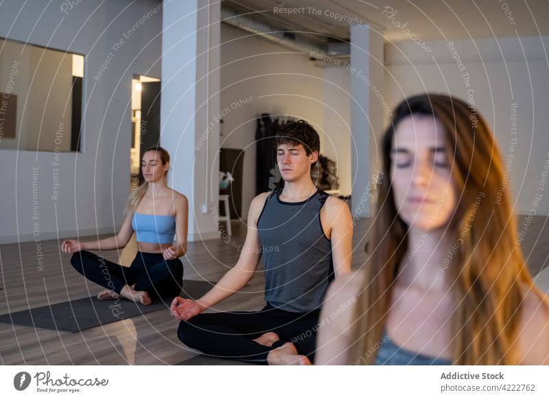Peaceful multiethnic people meditating together during yoga lesson class meditate mindfulness zen lotus pose studio multiracial woman diverse eyes closed asana