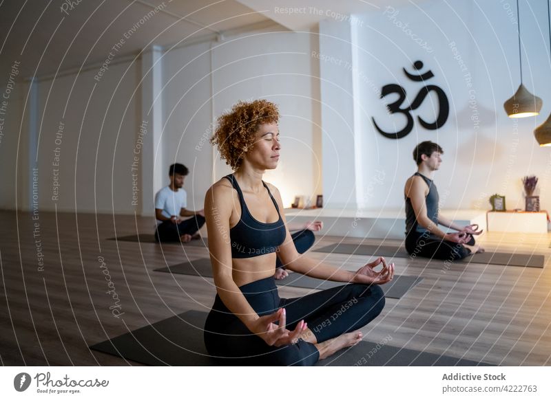 Peaceful multiethnic people meditating together during yoga lesson class meditate mindfulness zen lotus pose studio multiracial diverse black african american