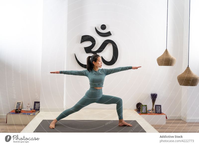 Asian woman doing yoga in Warrior pose in studio warrior pose practice grace slim flexible balance mindfulness female asian ethnic asana wellbeing mat vitality