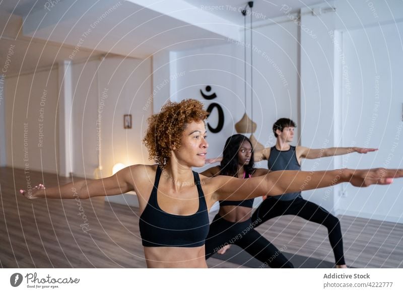 Ethnic black woman during group yoga lesson class people together practice warrior two multiracial multiethnic diverse african american balance asana