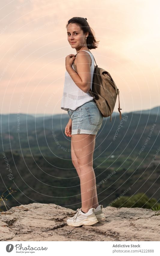 Smiling traveling woman with backpack in highlands at sunset traveler mountain sundown hiker smile female nature sky tourist vacation adventure freedom hill