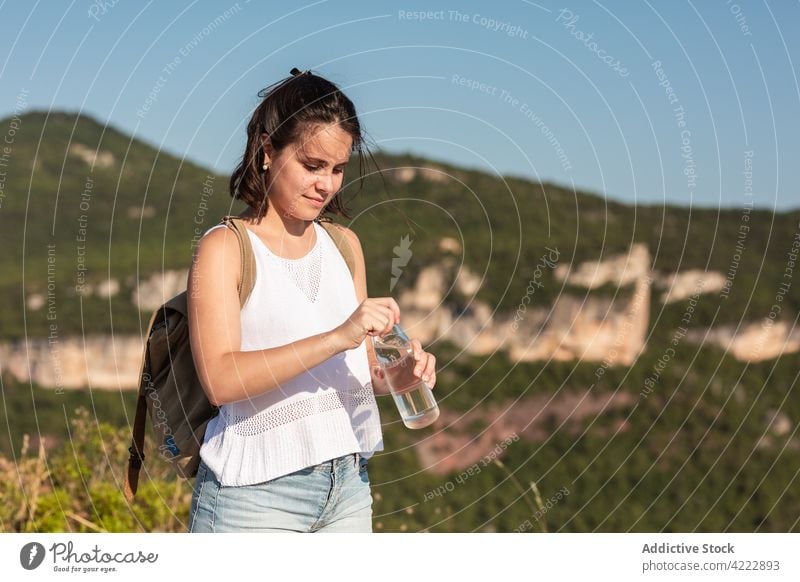 Traveling woman with a water bottle in highlands drink traveler hike mountain trekking refreshment thirst hydrate female nature tourism hiker journey summer