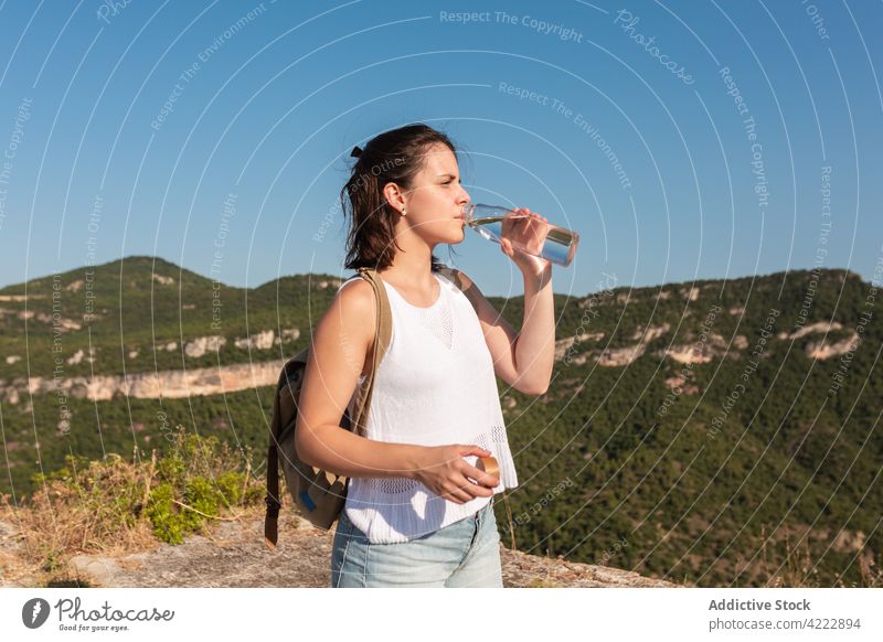 Traveling woman drinking water in highlands traveler hike mountain trekking refreshment thirst hydrate female nature tourism hiker journey summer activity