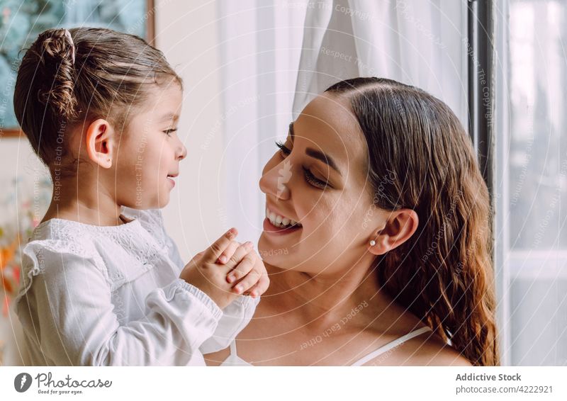 Woman with little child standing near window mother home parent daughter curious interesting together ethnic kid at home girl mom adorable motherhood woman cute