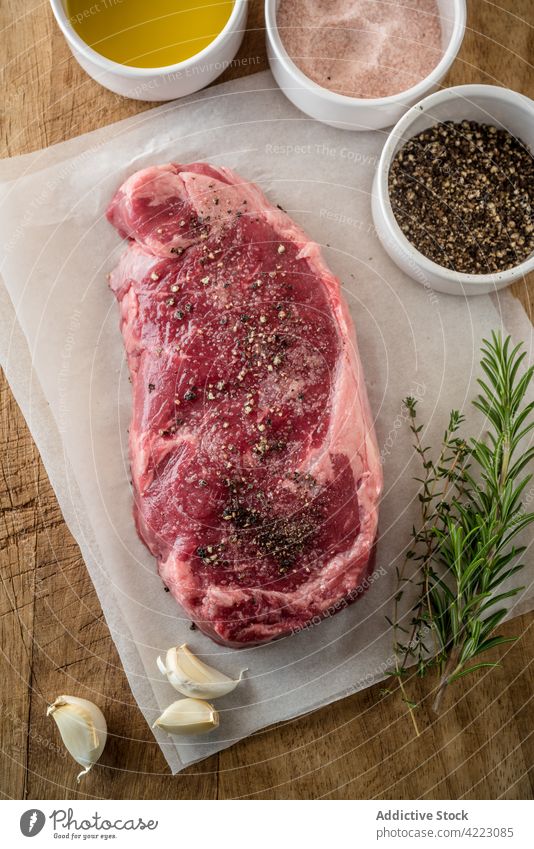 Raw beef steak with fresh rosemary and thyme sprigs near bowls with salt and pepper meat herb recipe natural product ingredient culinary protein uncooked