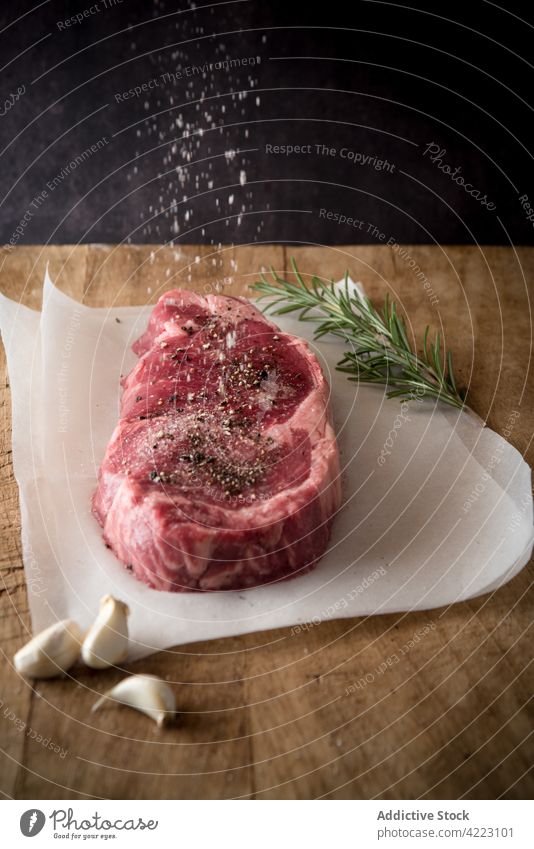 Uncooked meat steak with spices on parchment sheets beef salt condiment flow protein uncooked natural seasoning raw culinary recipe motion fluid rosemary sprig