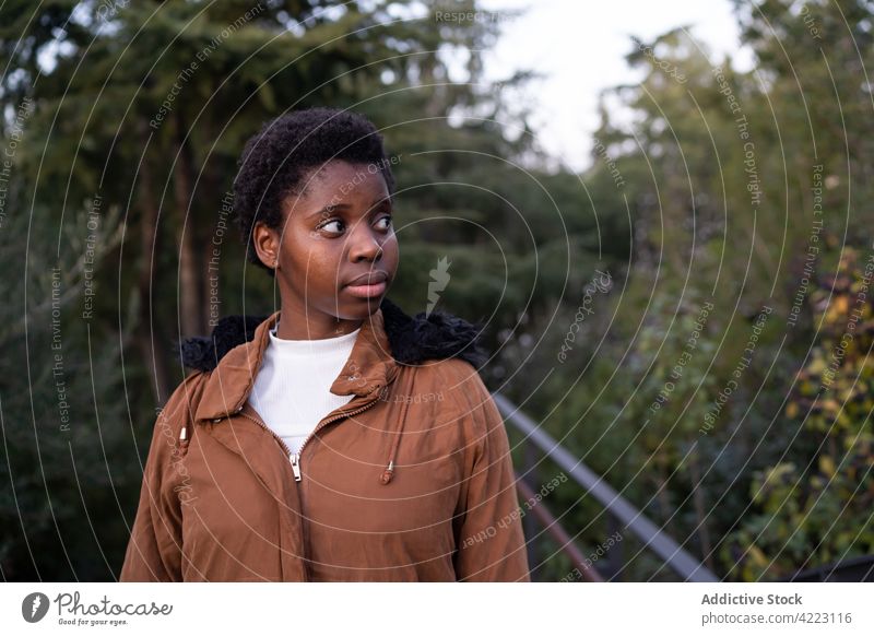 Black woman standing in lush spring park garden calm warm clothes season dreamy unemotional casual appearance enjoy pleasant barcelona spain verdant forest