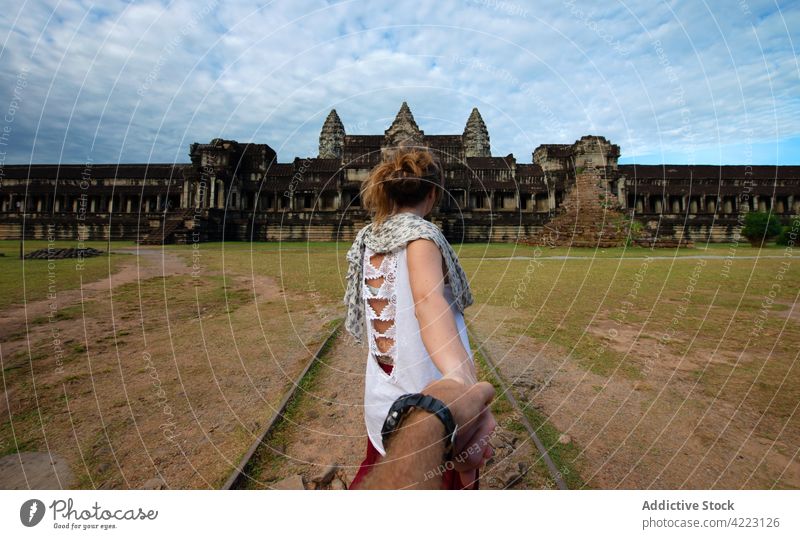 Unrecognizable couple against ancient oriental temple complex in town holding hands follow me angkor wat architecture historic heritage travel religion tourist