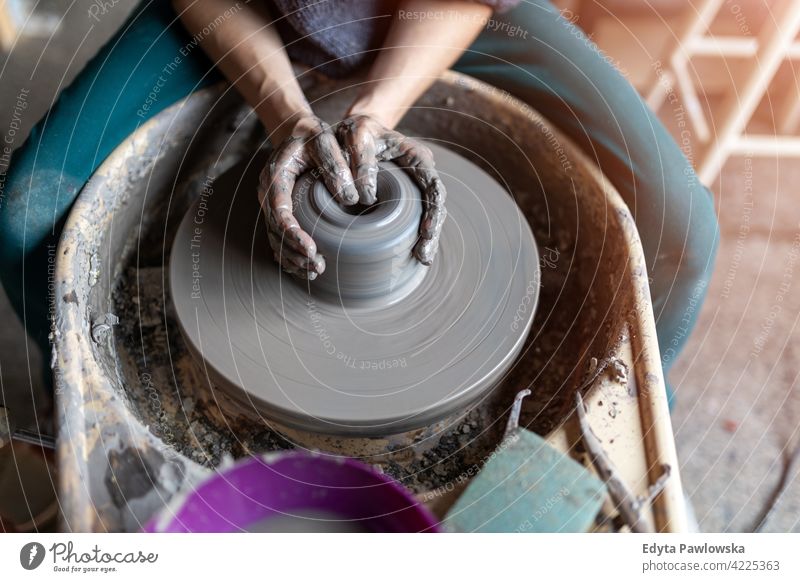 Woman making ceramic work with potter's wheel pottery artist ceramics working people woman young adult casual attractive female happy Caucasian enjoying