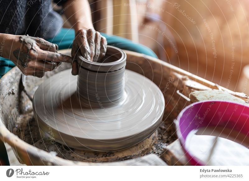 Woman making ceramic work with potter's wheel pottery artist ceramics working people woman young adult casual attractive female happy Caucasian enjoying