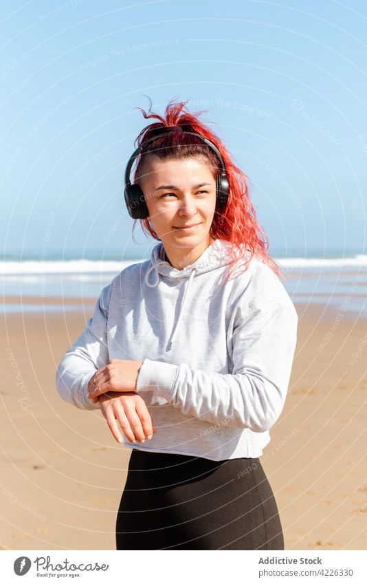 Sportswoman in headset on sandy sea shore athlete headphones contemplate healthy lifestyle wellness vitality seashore portrait using gadget device listen music