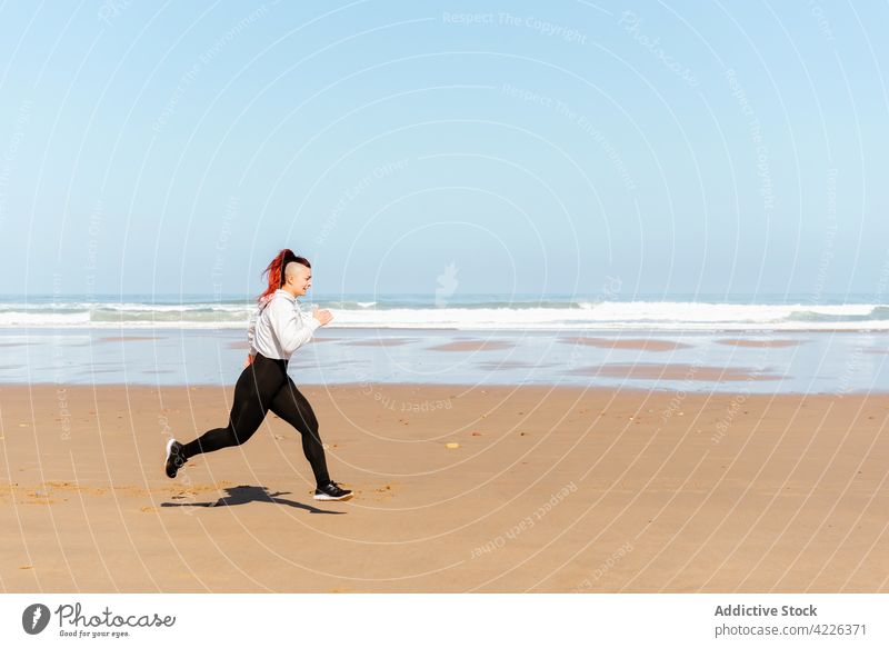 Fast runner jogging on sandy sea beach during workout jogger seashore sport training cardio activity woman sportswoman exercise fast motion endurance motivation