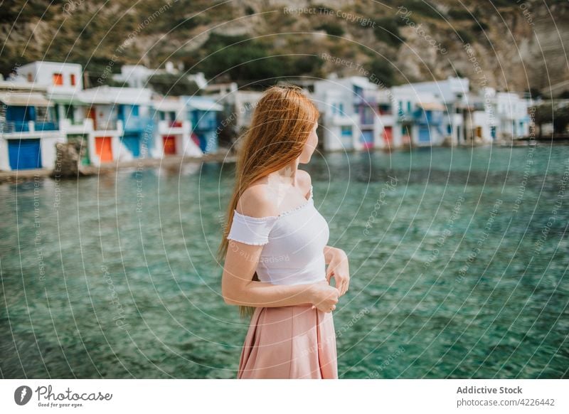 Young faceless woman standing in small coastal village sea klima admire sunny resort seashore house peaceful vacation holiday style milos greece summer serene