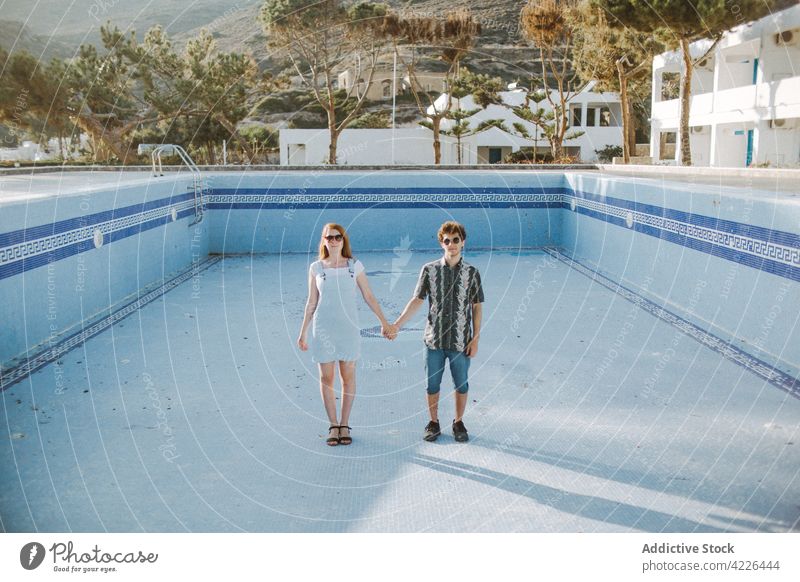 Young couple standing together in pool without water empty holding hands calm resort relationship drained romantic adamantas milos unusual vacation young love