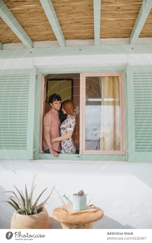 Young couple hugging near window in small cottage embrace house tender in love village relationship romantic sunny together affection adamantas milos greece