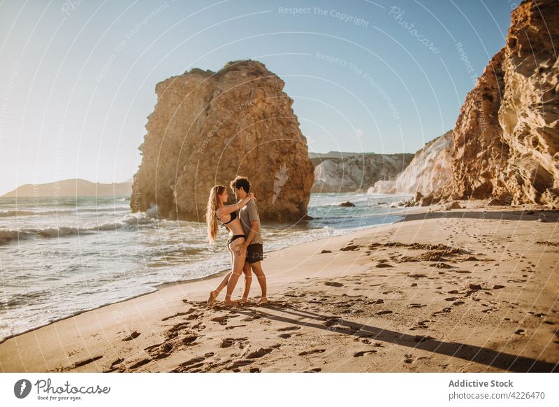 Young couple hugging on sunny rocky seacoast in love relationship nature beach honeymoon romantic resort embrace fyriplaka milos greece relax vacation together
