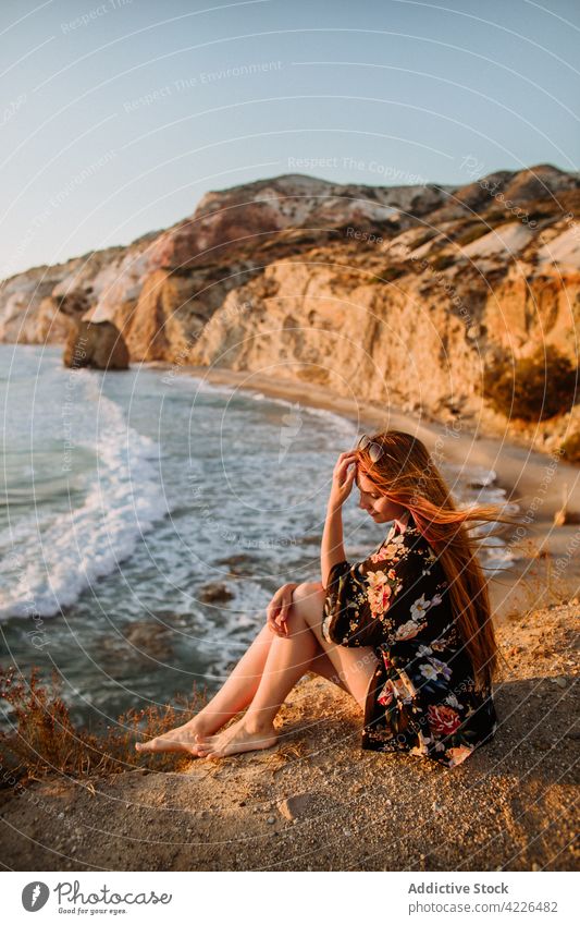 Woman sitting on scenic rocky coast woman seashore nature touch hair resort coastline feminine picturesque cliff fyriplaka admire traveler style milos greece