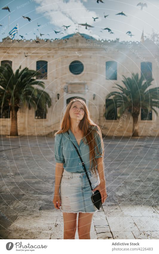 Dreamy woman standing near old stone building and flying birds facade traveler architecture content dreamy sightseeing attract exterior trip crete heraklion