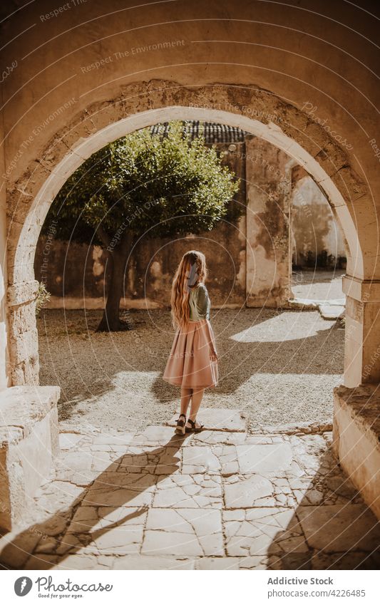 Anonymous woman standing near historic building arch old architecture ancient street medieval summer heraklion crete greece travel young sunlight dress style