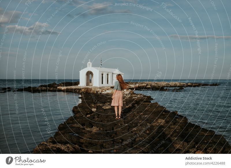 Unrecognizable woman standing near white chapel located on stony islet st nickolas chapel church travel nature attract sightseeing architecture explore traveler