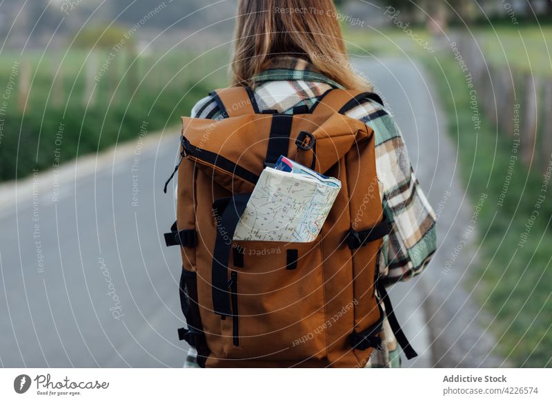 Crop tourist with paper map in rucksack on road route direction wanderlust explore travel woman countryside hiker itinerary trip traveler guide roadway