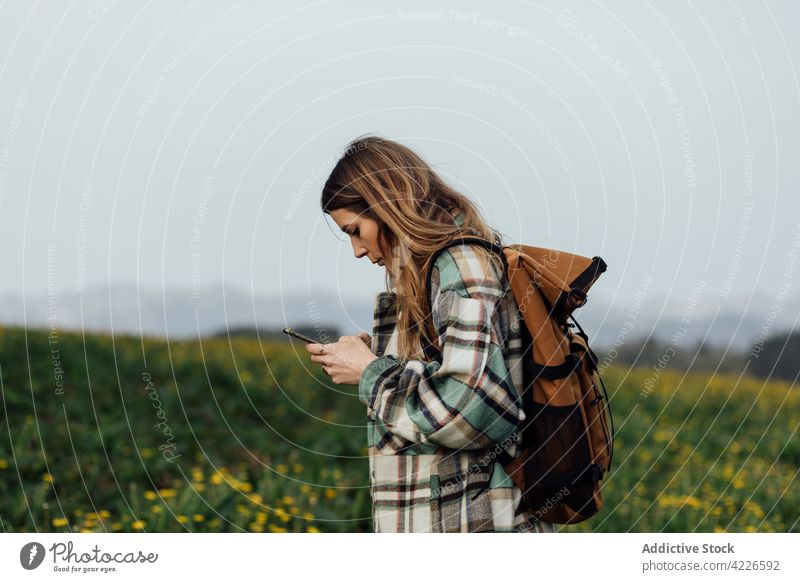 Backpacker with navigation app on smartphone in countryside field hiker gps application route direction woman using gadget device orientate navigate cellphone