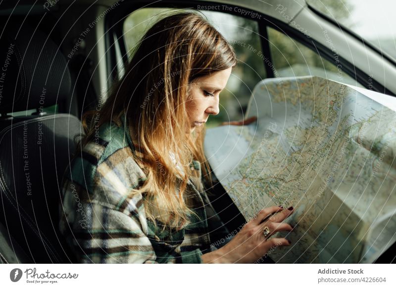 Driver writing on paper map in car during trip driver write route location destination guide orientate woman pen take note traveler countryside wanderlust