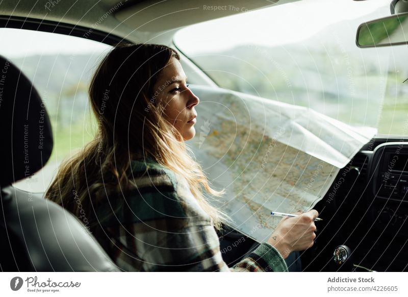 Driver with map in car during trip driver route location destination guide orientate woman traveler countryside wanderlust tourist navigate direction paper