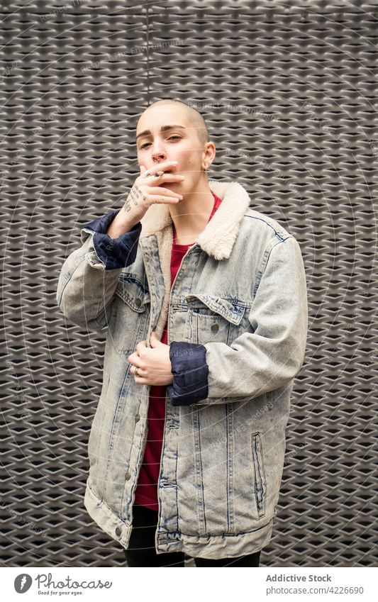 Transsexual person with tattoo smoking cigarette on gray background transgender smoke self confident vain individuality cool street style portrait queer