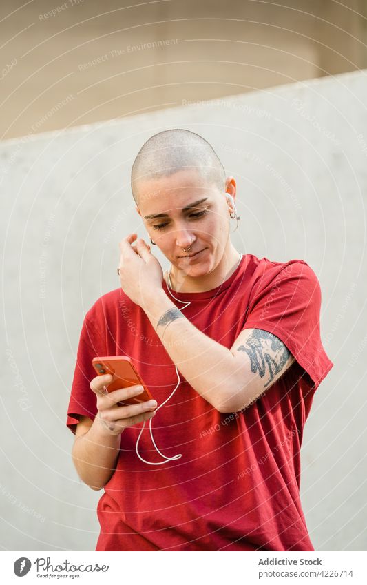 Lesbian woman with smartphone and tattoos on city street lesbian earphones accept listen music portrait using gadget device song androgynous audio melody sound