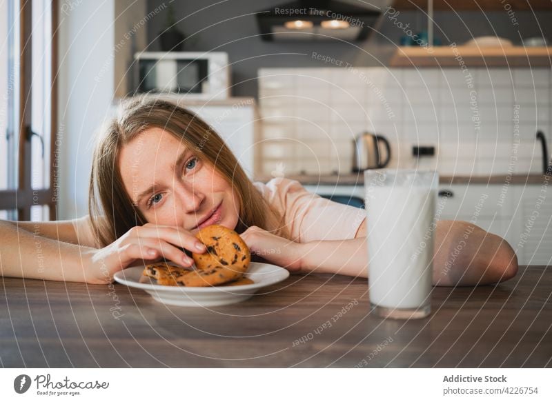 Woman with delicious oat cookies and milk at kitchen table woman breakfast sweet treat enjoy nutrient portrait biscuit house drink charming home ornament