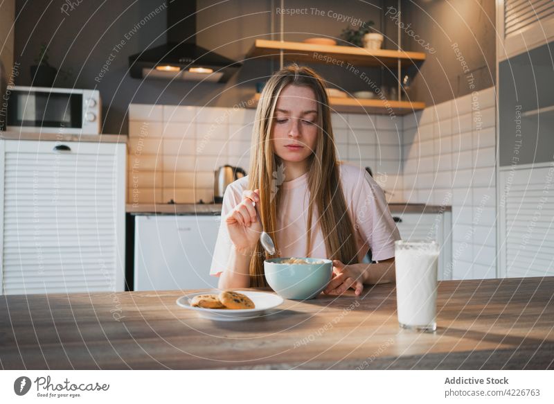 Woman eating delicious cereal for breakfast at home woman corn ring sweet nutrition mouth opened portrait kitchen portion table domestic spoon bowl enjoy