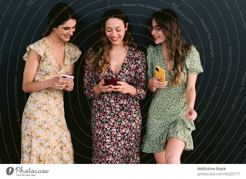 Happy girlfriends in stylish dresses with smartphones on pavement best friend style trendy friendship happy feminine women using gadget spend time device
