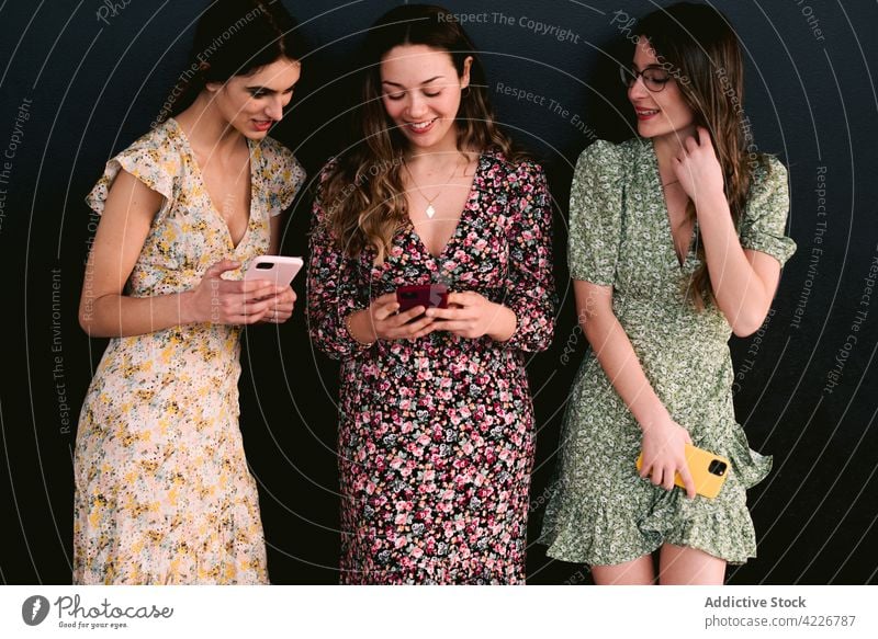 Happy girlfriends in stylish dresses with smartphones on pavement best friend style trendy friendship happy feminine women using gadget spend time device