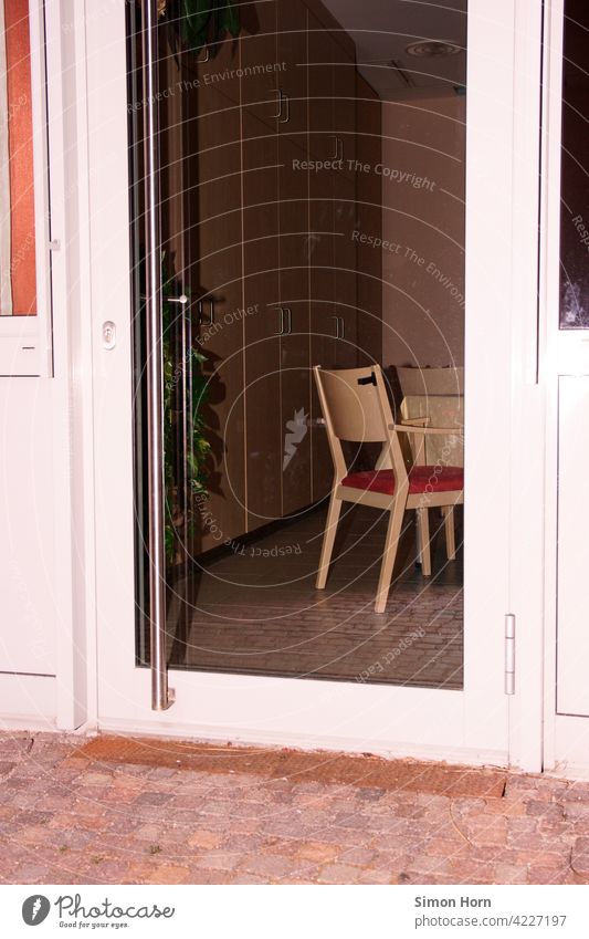 View through a glass door to a deserted dining room Glass door insulation Dining hall Chair Introverted observation Home for the elderly Participation Company