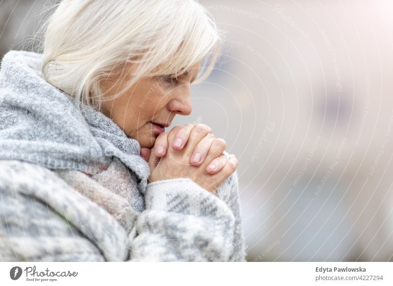 Portrait of senior woman praying hands wishing religion hope worried grief grieving depressed depression sad mourning seniors pensioner pensioners casual