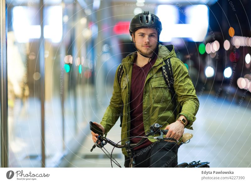 Young man on bicycle in the city at night male boy student tourist urban street people young adult casual Caucasian enjoying one person confident dusk evening