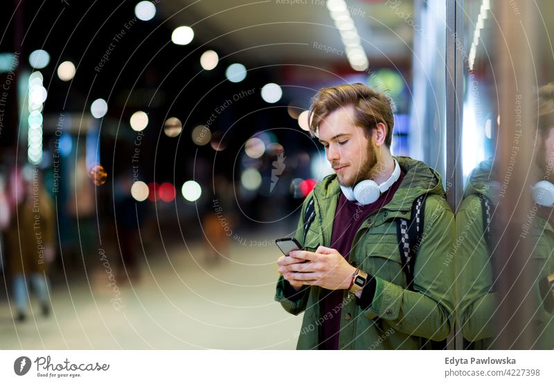 Young man using smartphone on urban street at night male boy student tourist city people young adult casual Caucasian enjoying one person confident dusk evening
