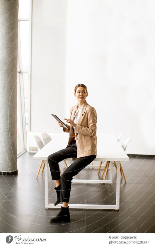 Young woman holding digital tablet in modern office adult attractive beautiful business businesswomen display electronic female happy indoors internet looking