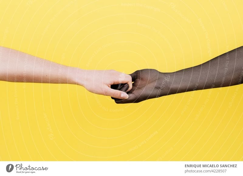 White hand and black hand clasped on yellow background people friendship together african international relationship skin unity copy space male agreement arms