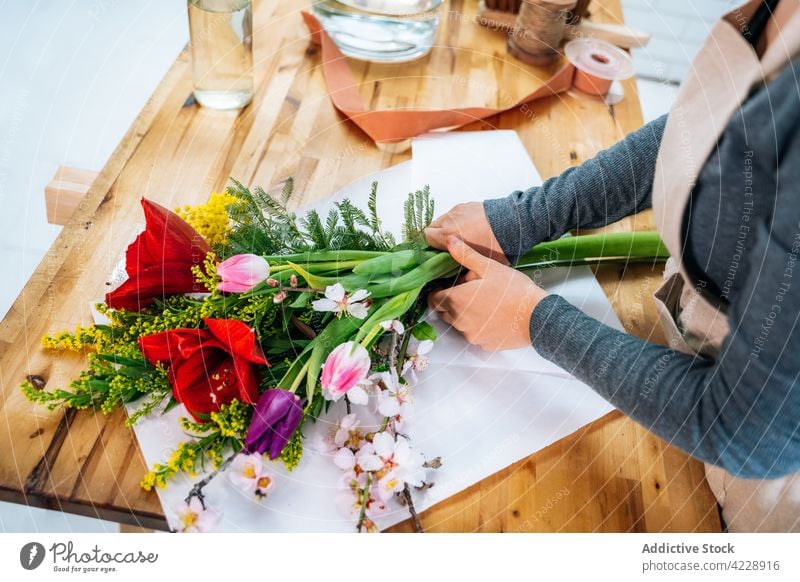 Anonymous female florist creating composition with assorted fresh flowers woman bouquet work plant floral workplace arrangement occupation decor young casual