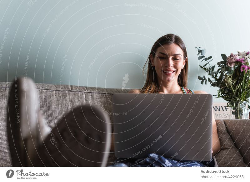 Smiling woman with laptop on couch at home internet online content sofa using gadget device interact cheerful spend time weekend netbook show surfing lifestyle