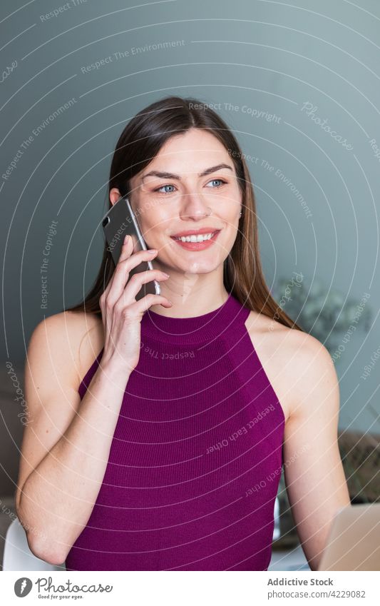 Smiling woman speaking on smartphone at home toothy smile sincere feminine charming portrait using gadget device cellphone phone call talk spare time house