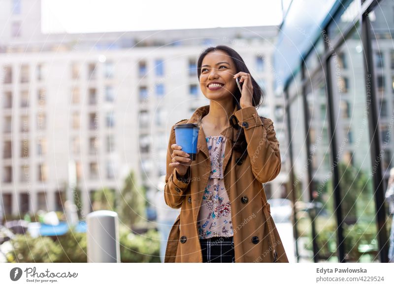 Young woman with smartphone and coffee in the city Filipino urban street active people young adult casual attractive female happy asian enjoying one person