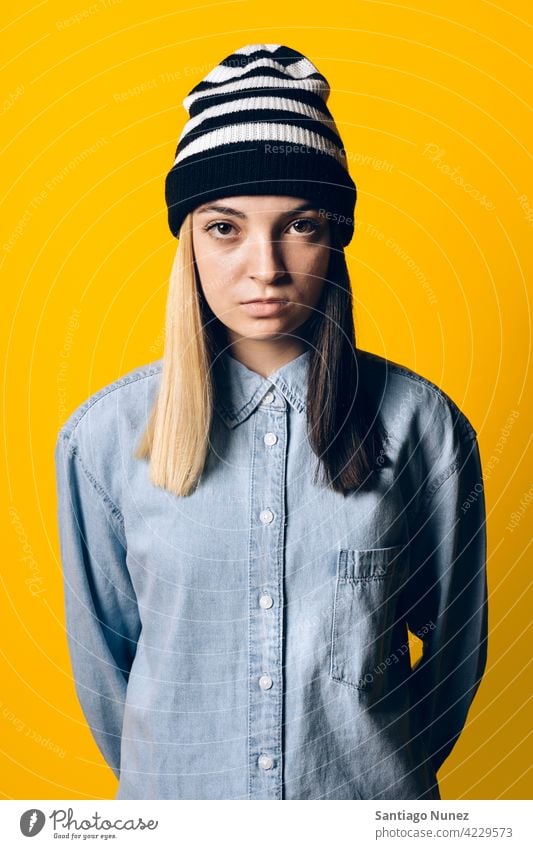 Serious Girl Wearing Hat Portrait studio yellow background portrait looking at camera expression colorful hair style casual young girl female serious