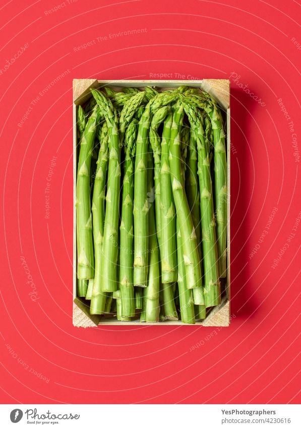 Green asparagus in a wooden box top view, isolated on a red background. above agriculture bio bunch color cooking crate cuisine cut out diet dinner european