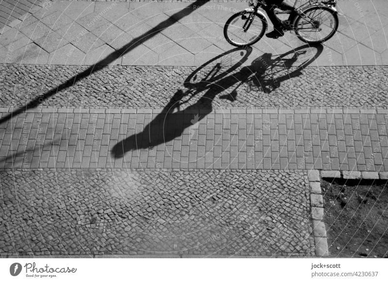 Cycling on the pavement Sidewalk Drop shadow Sunlight Silhouette Shadow play Structures and shapes Lanes & trails Paving stone Paving tiles Cycle path Bicycle